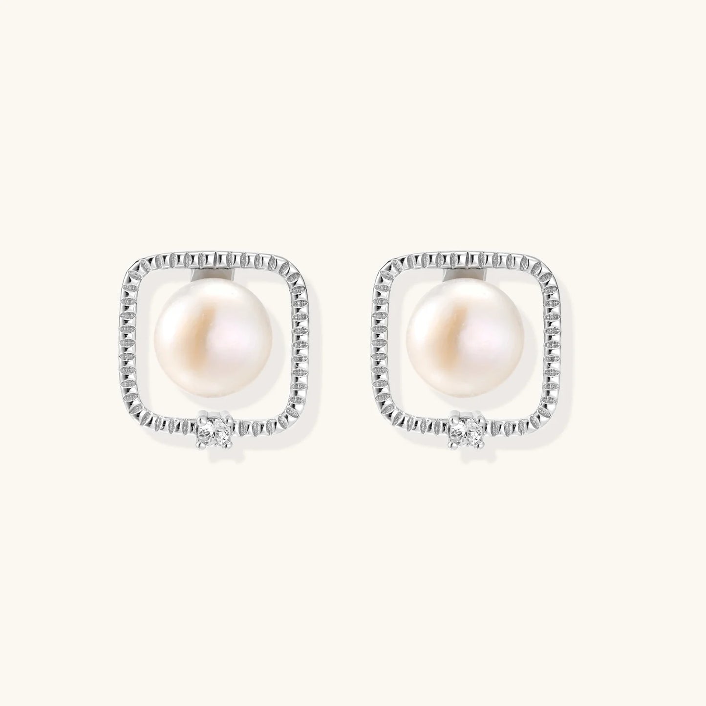 Rhodium-plated silver stud earrings with cushion frame, centered freshwater pearl, and tiny crystal accent
