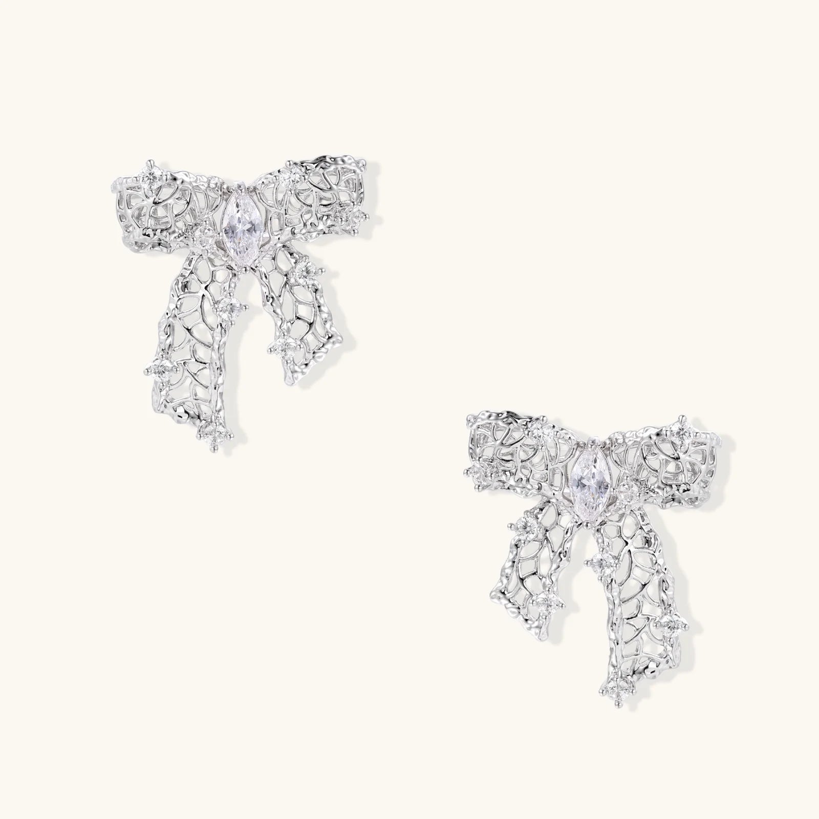 Filigree bow-shaped earrings with marquise center stone and lattice ribbon tails in gold and silver finishes