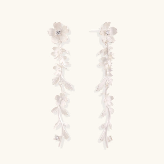 Long sterling silver drop earrings with delicate floral vine design and crystal accents on white background