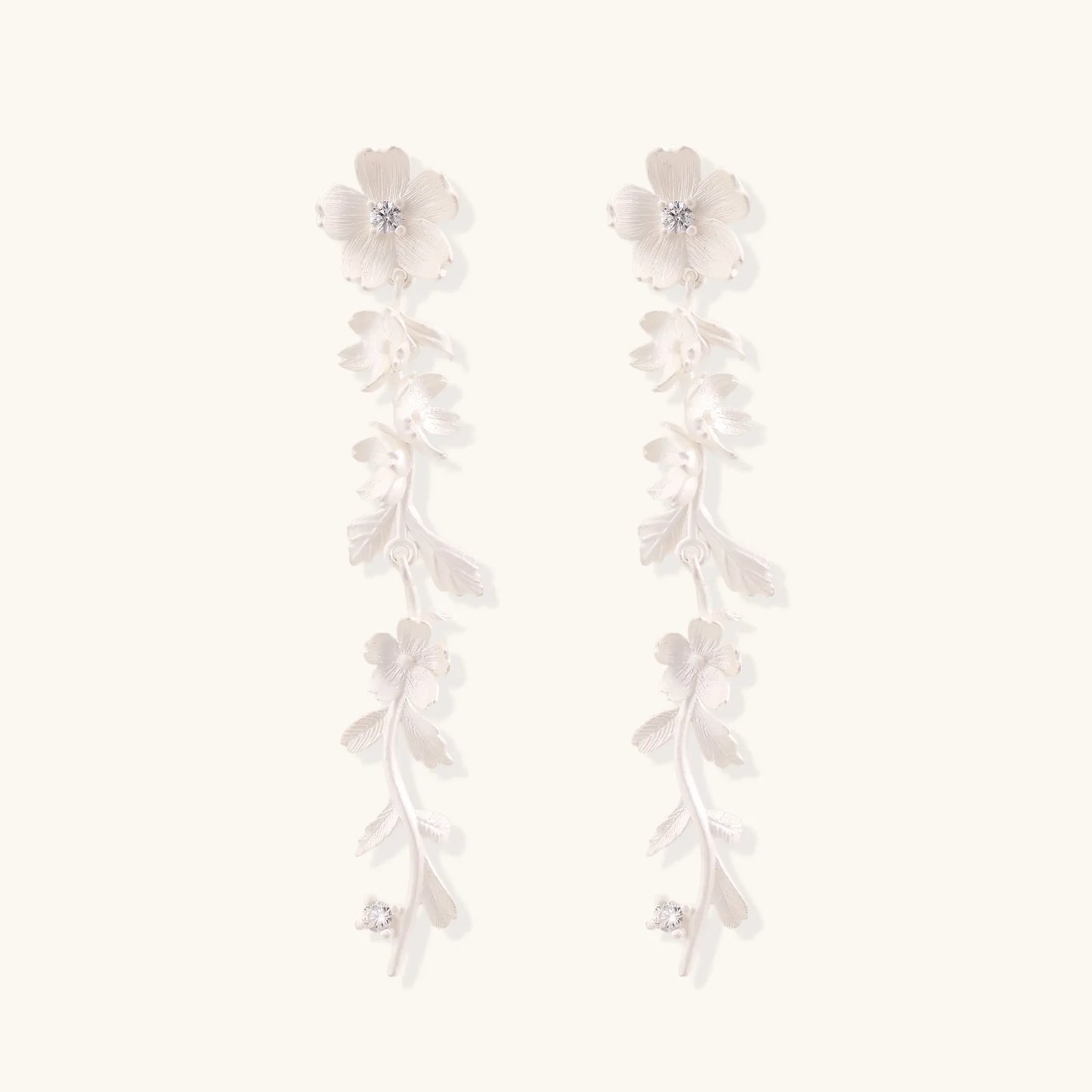 Long sterling silver drop earrings with delicate floral vine design and crystal accents on white background
