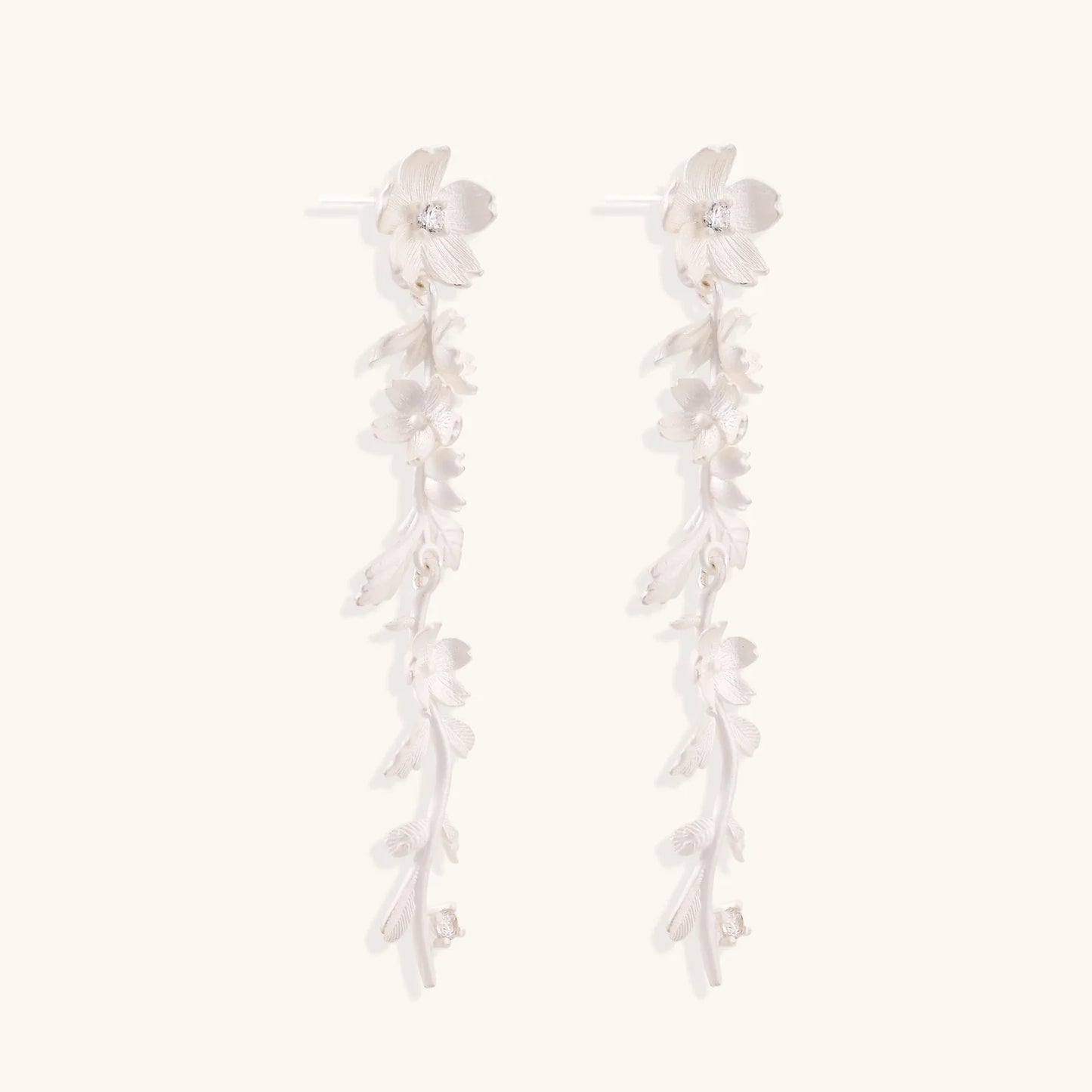 Long sterling silver drop earrings with delicate floral vine design and crystal accents on white background