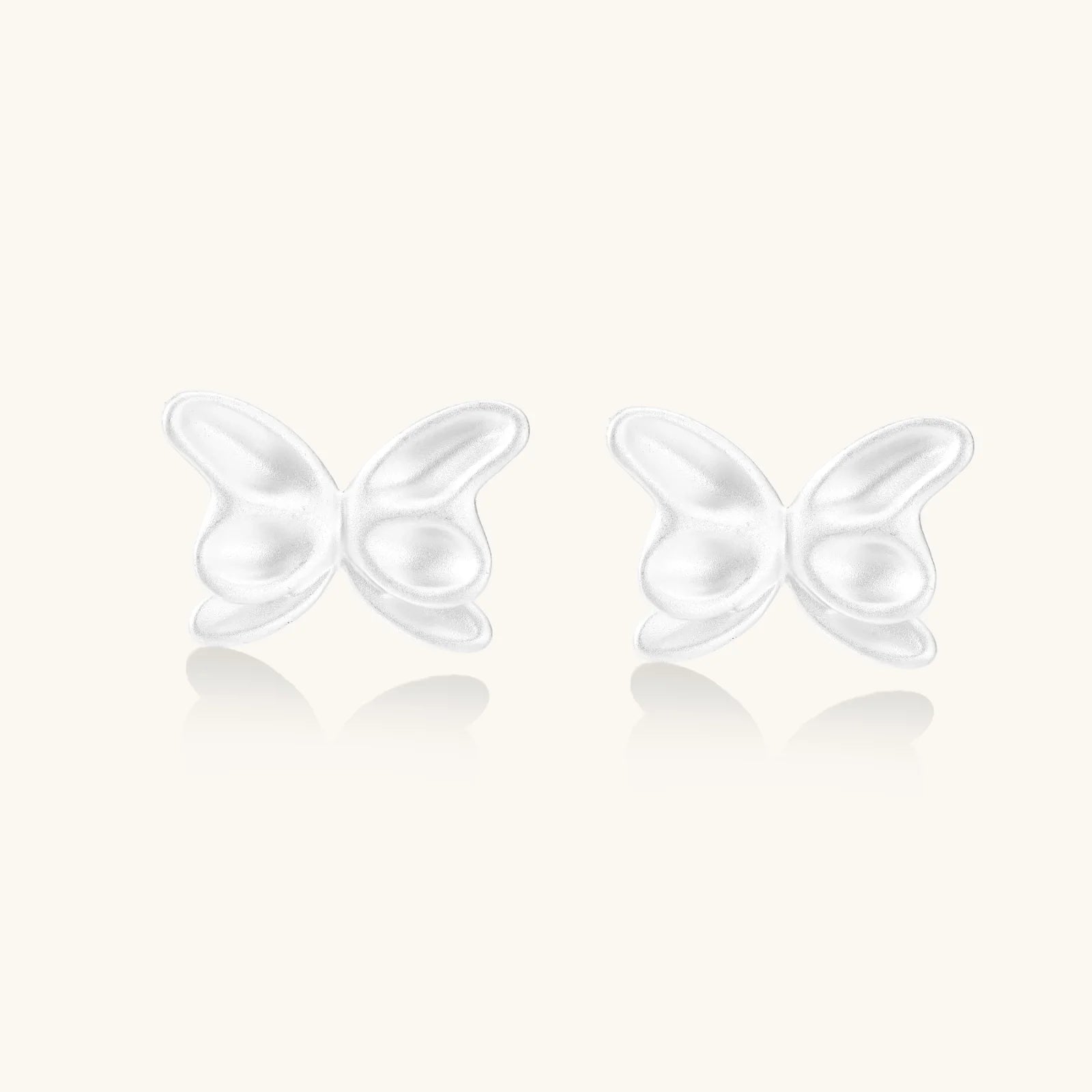 Pair of translucent butterfly-shaped stud earrings with frosted finish and dimensional wing details on white background