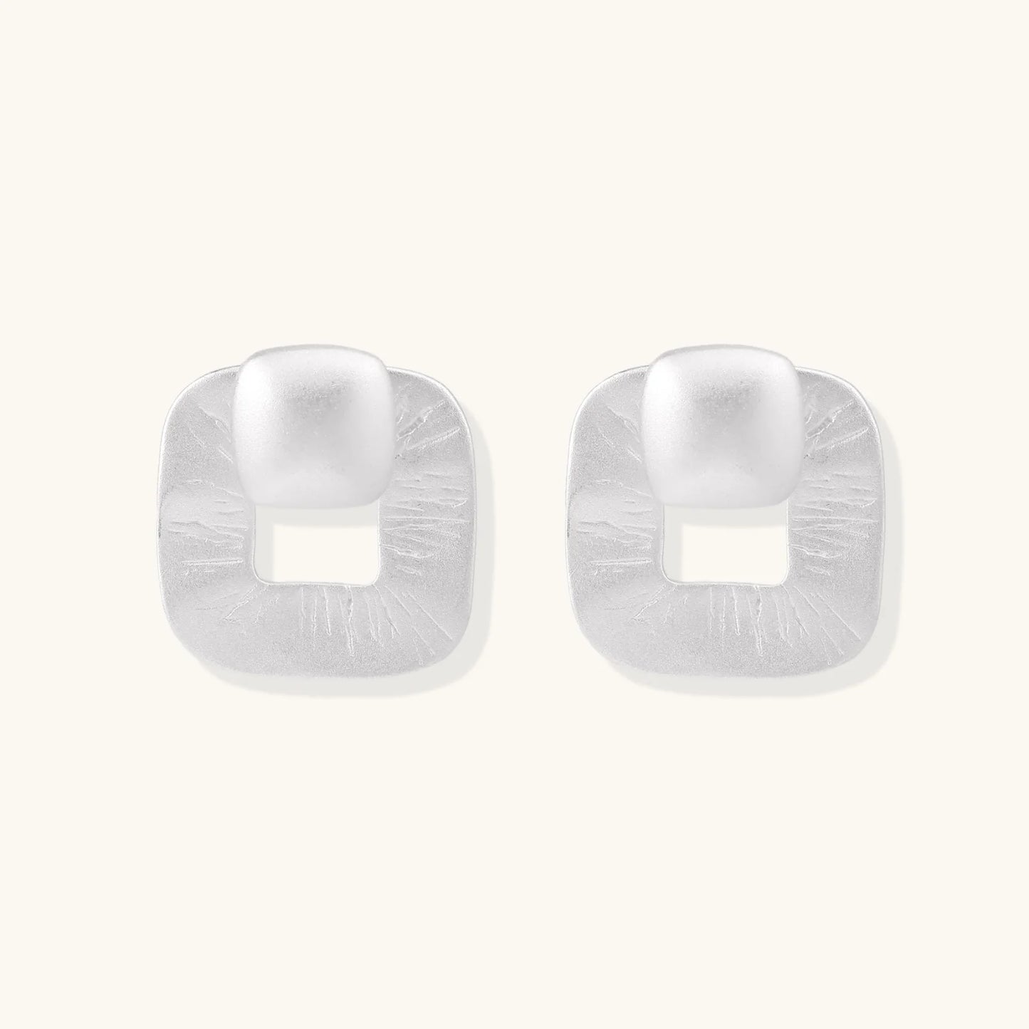 Pair of geometric sterling silver earrings with frosted square frames and glossy rounded studs on white background