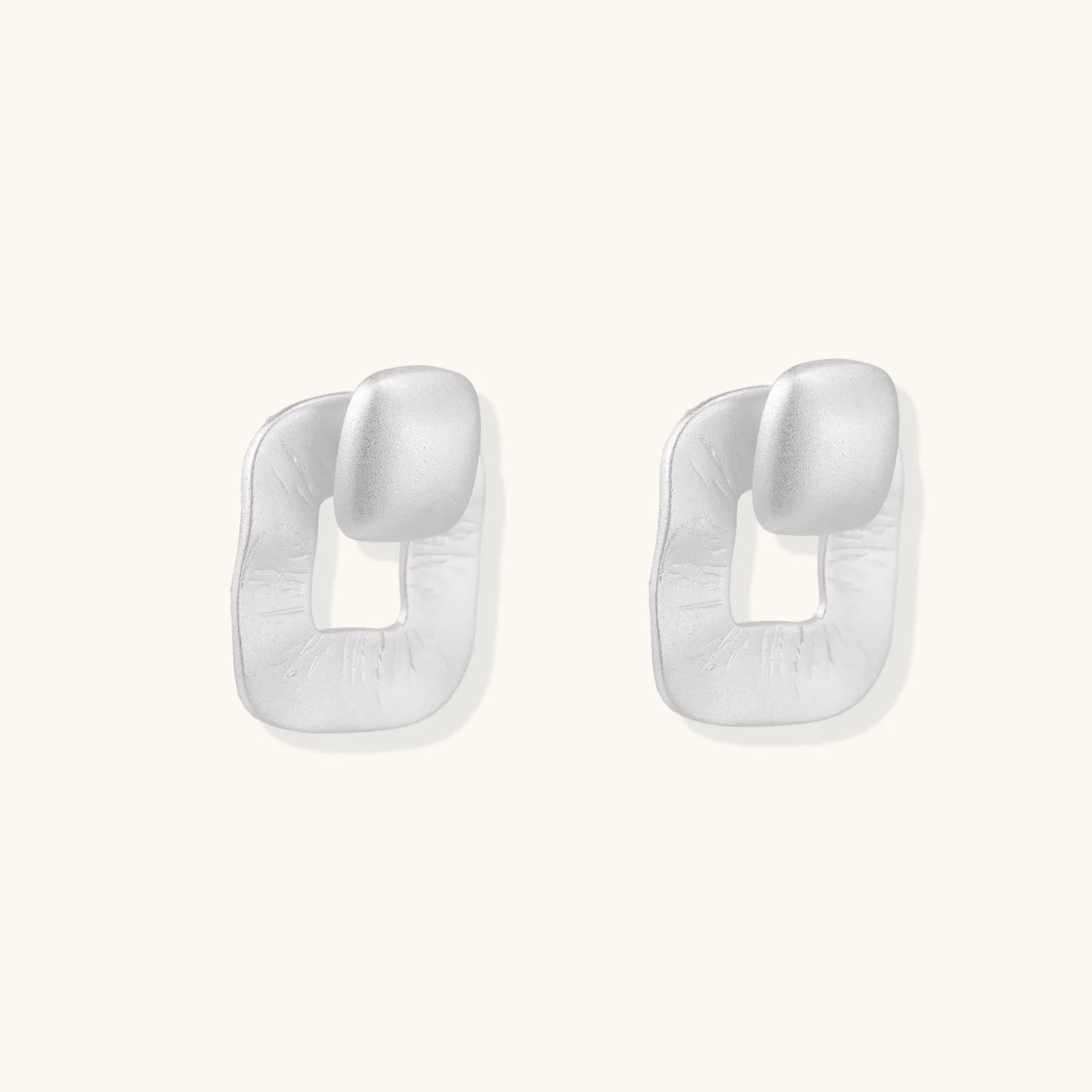 Pair of geometric sterling silver earrings with frosted square frames and glossy rounded studs on white background