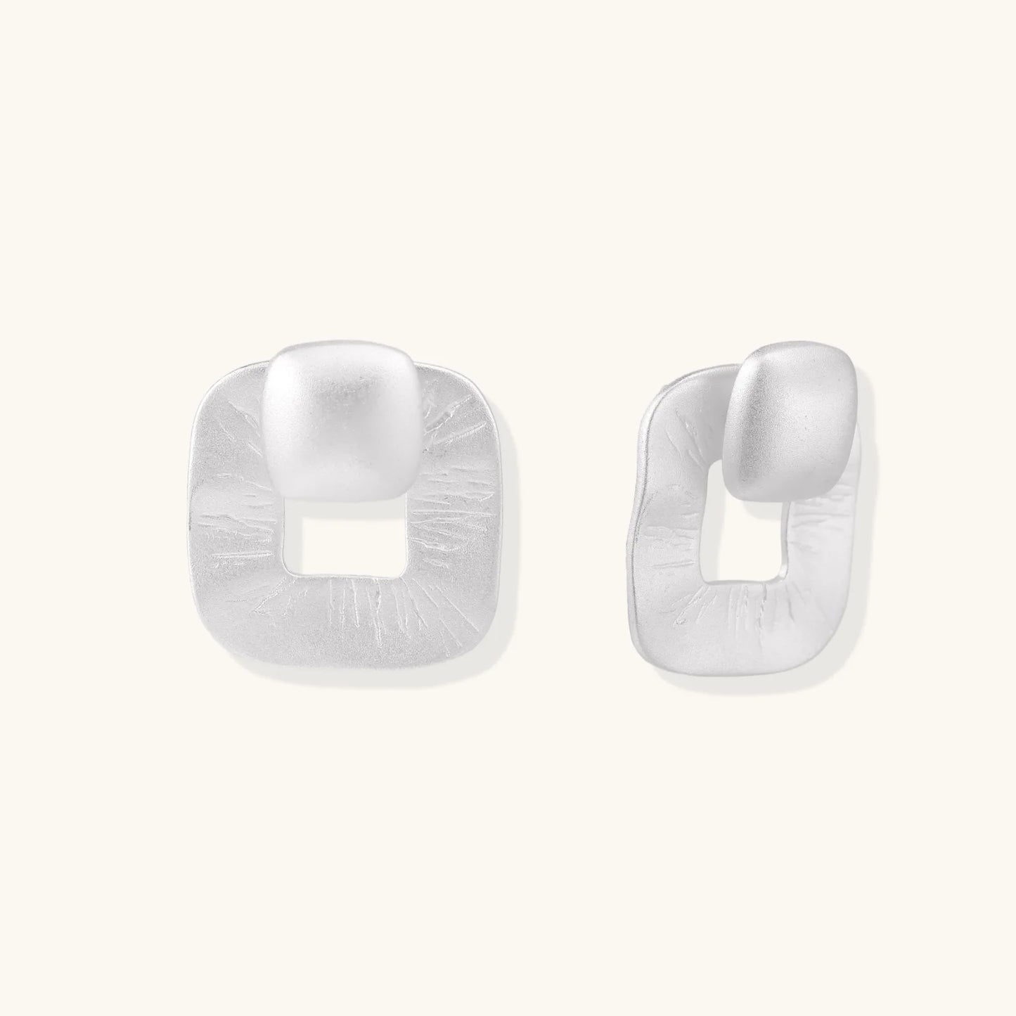 Pair of geometric sterling silver earrings with frosted square frames and glossy rounded studs on white background
