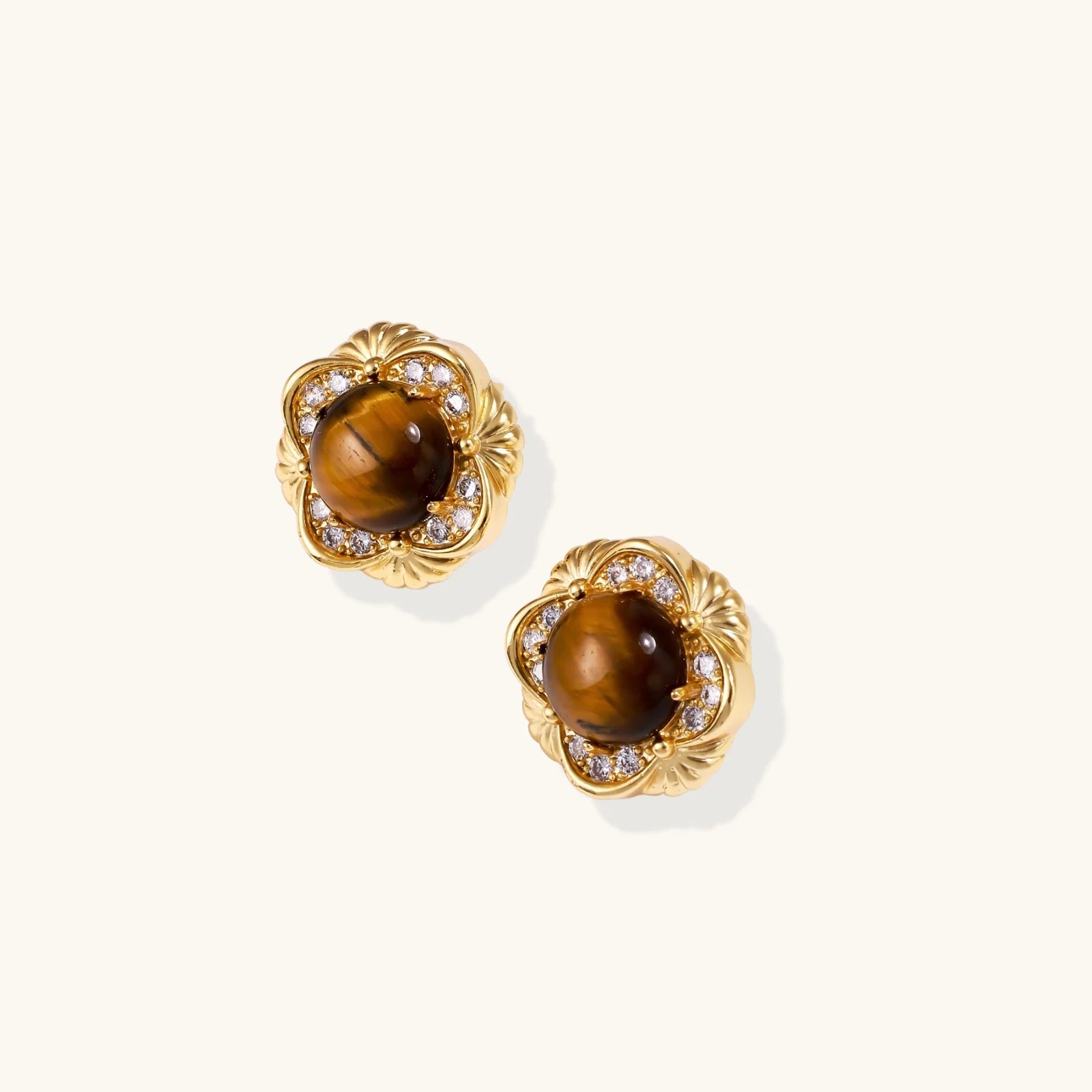 Gold-plated stud earrings with ornate floral frames surrounding cabochon tiger's eye stones and zirconia accents