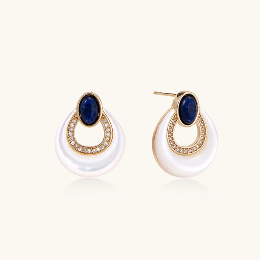 Gold drop earrings with oval lapis lazuli, crystal-paved frame, and iridescent mother-of-pearl teardrop on cream background