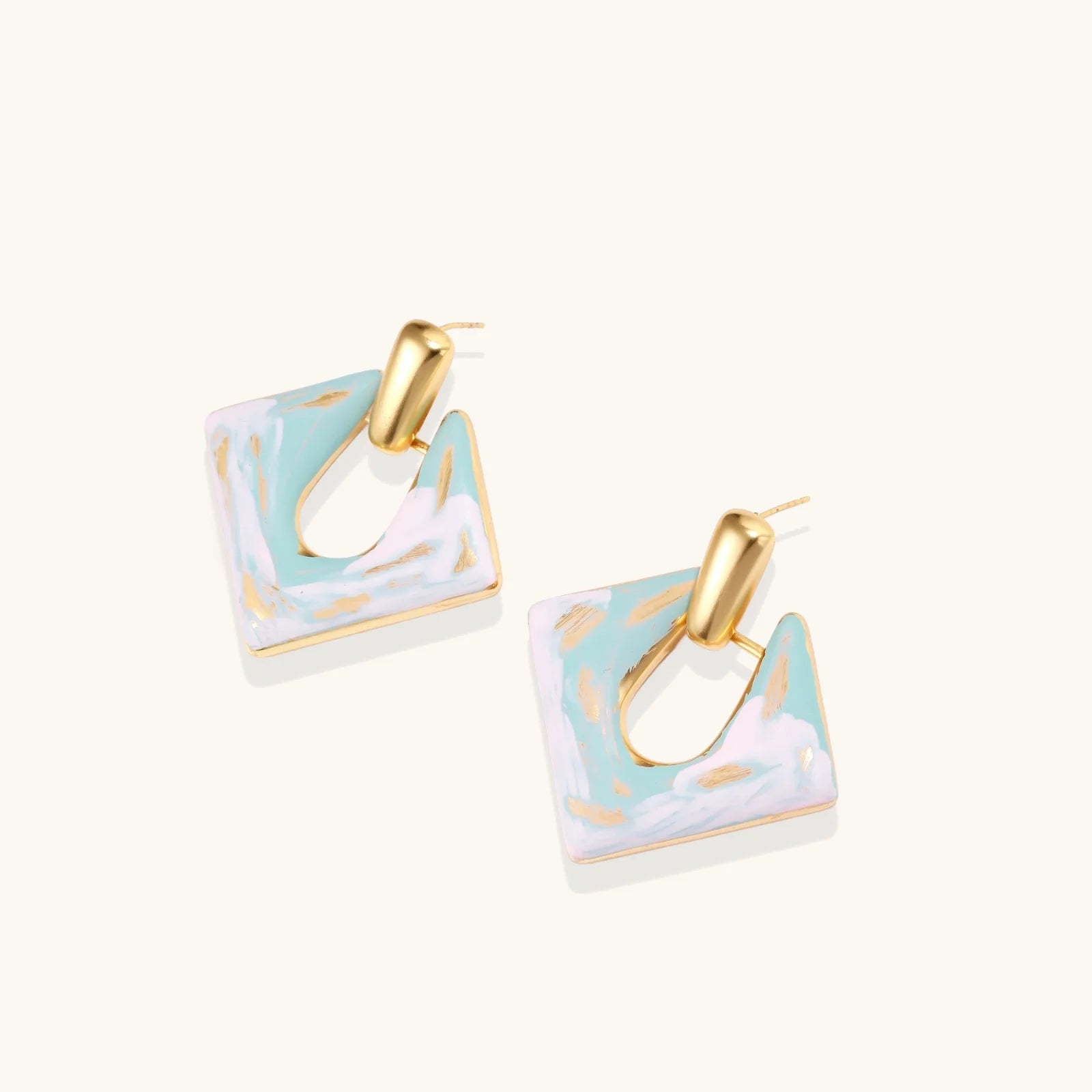 Geometric square enamel earrings with marbled turquoise and lavender pattern, gold U-shaped connector on cream background.