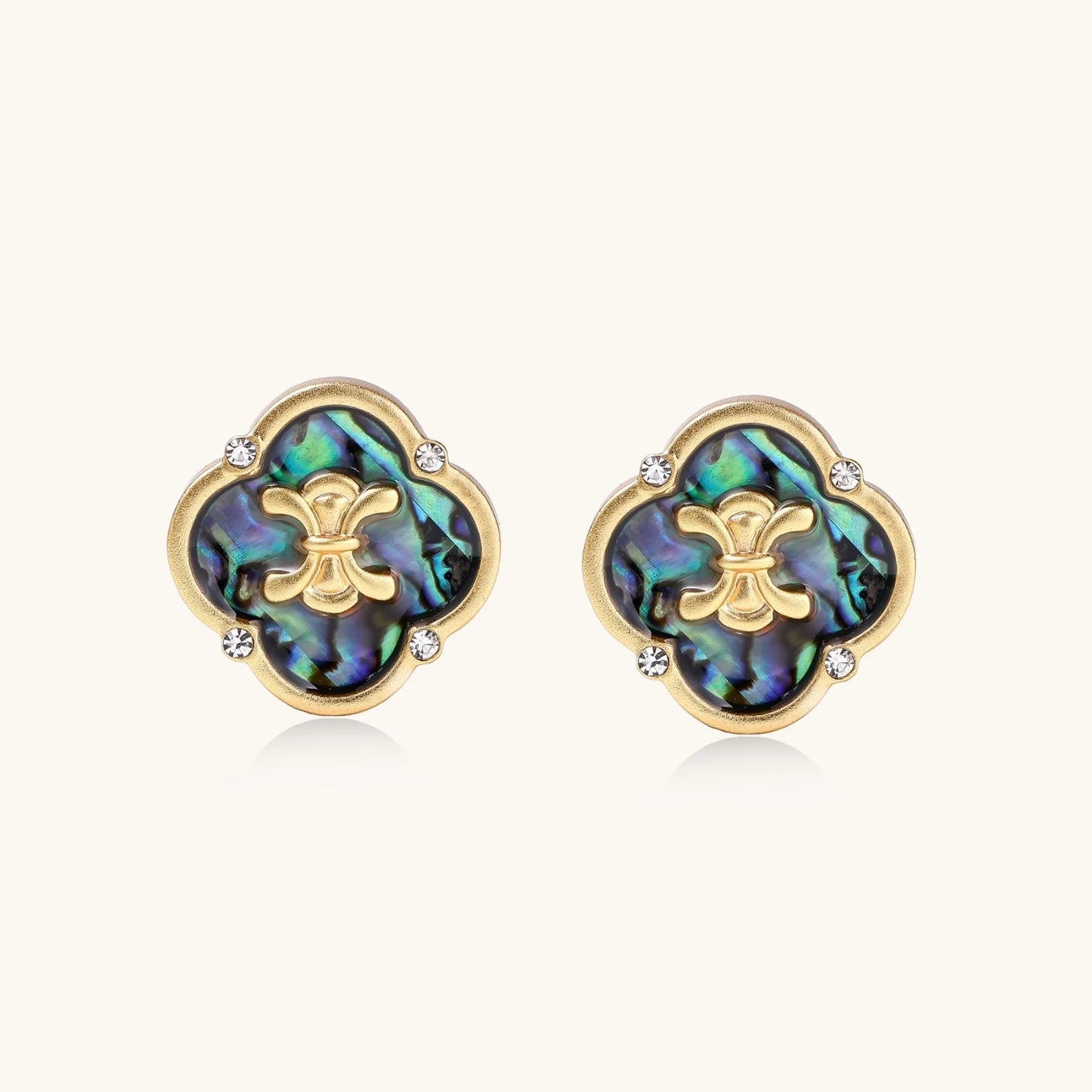 Gold quatrefoil stud earrings with iridescent abalone shell inlay and fleur-de-lis center, accented by four crystals