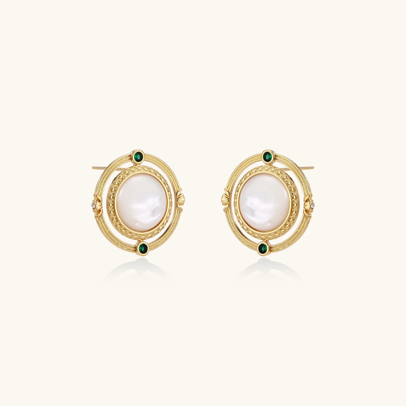 Circular gold stud earrings with iridescent mother-of-pearl center and green zirconia accents on cream background.