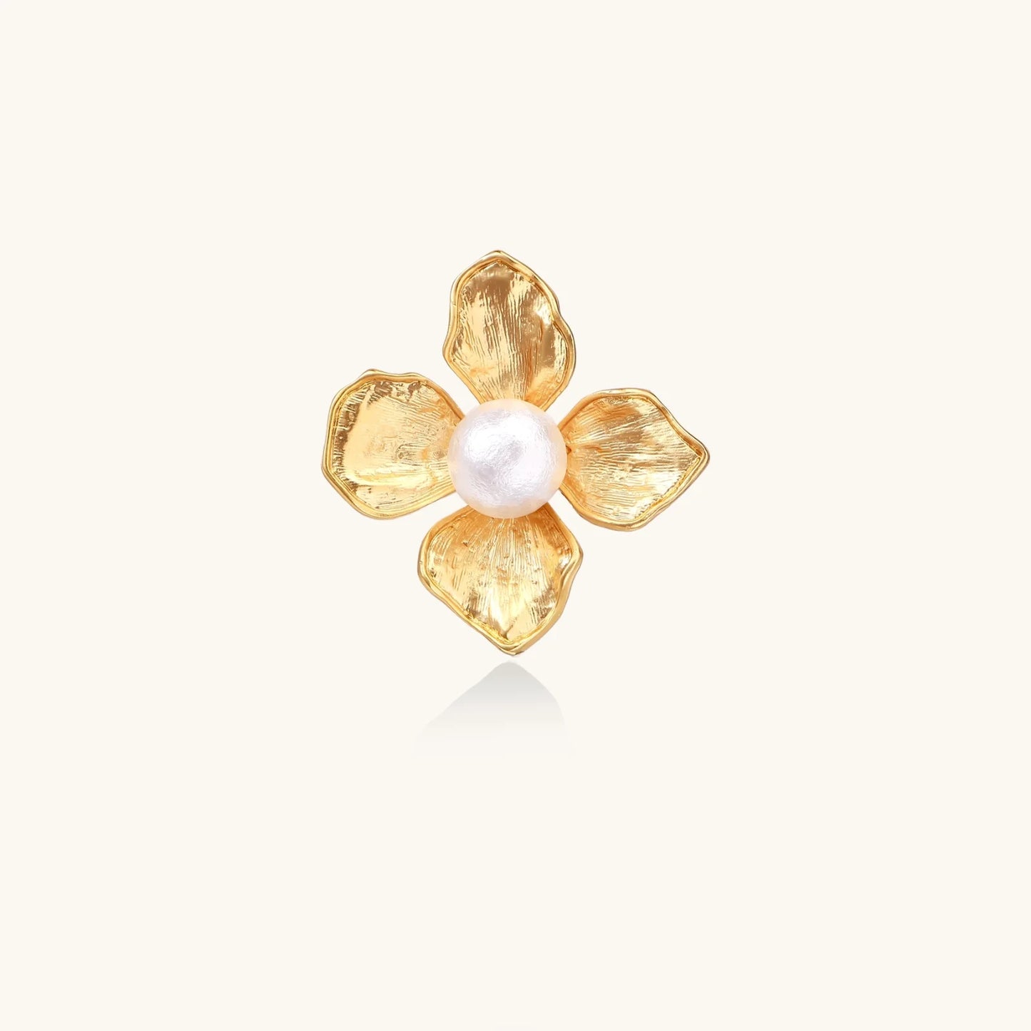 Gold-plated flower ring with textured petals and white cotton pearl center on cream background