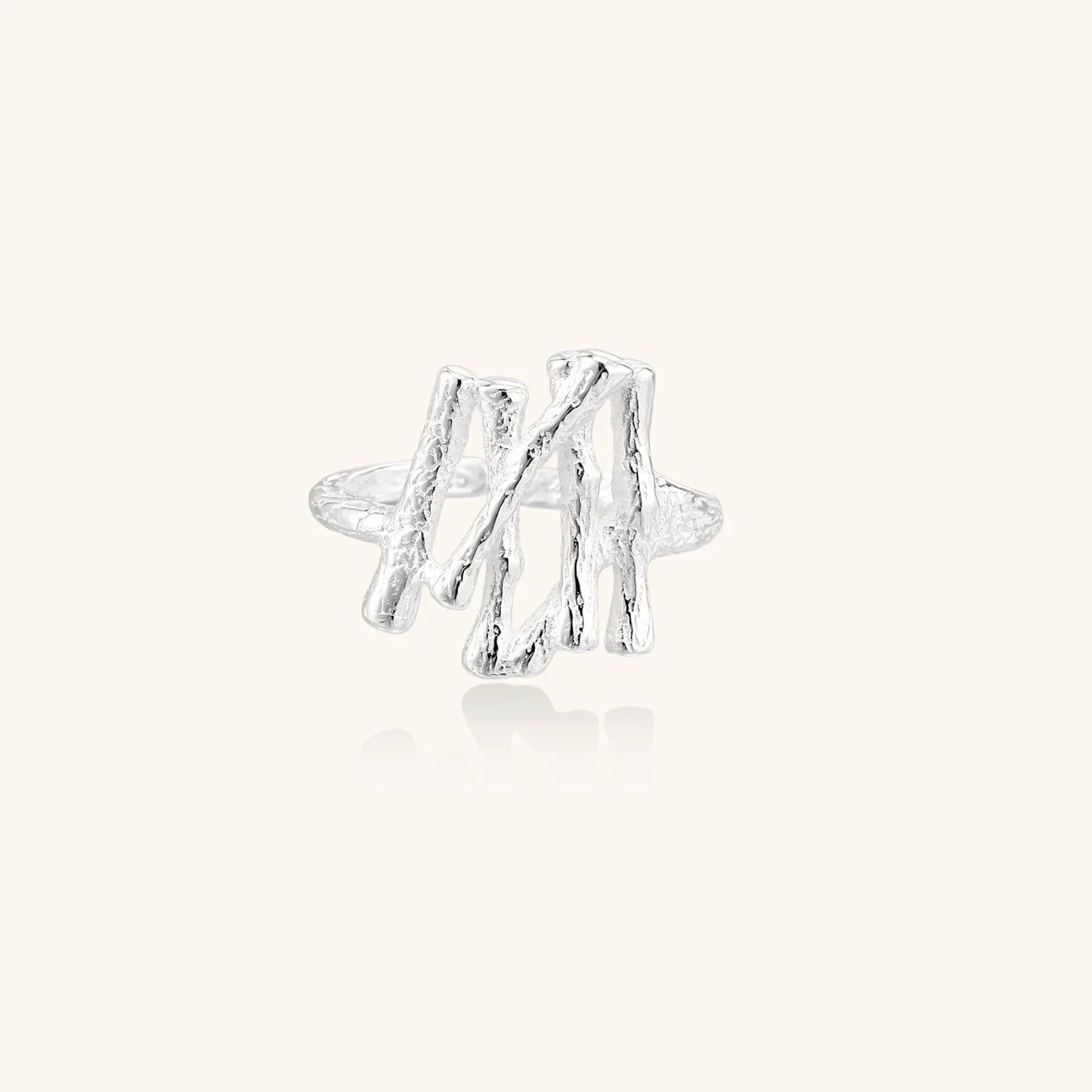 Sculptural sterling silver ring with organic branch design and textured surfaces on cream background