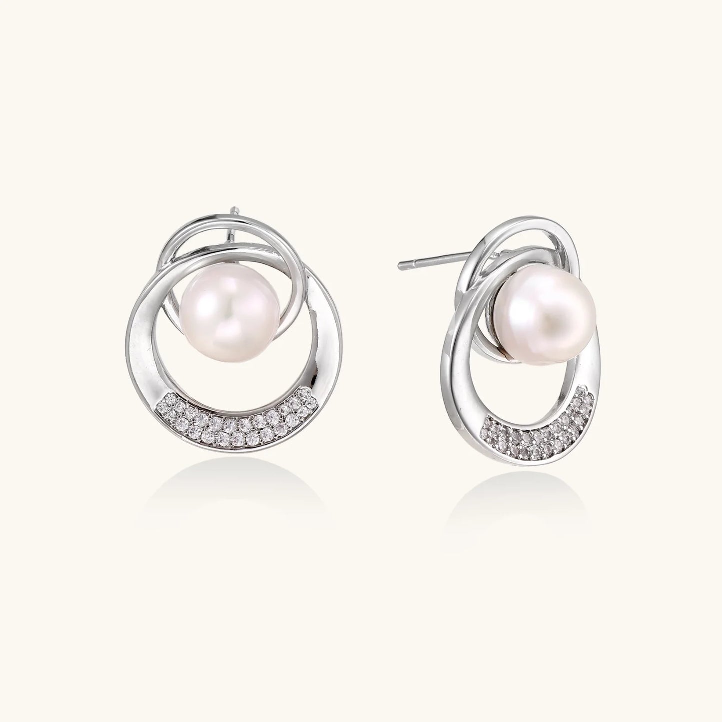 White gold-plated brass earrings with circular design, freshwater pearl center, and diamond accents