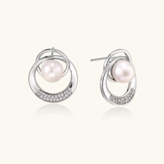 White gold-plated brass earrings with circular design, freshwater pearl center, and diamond accents