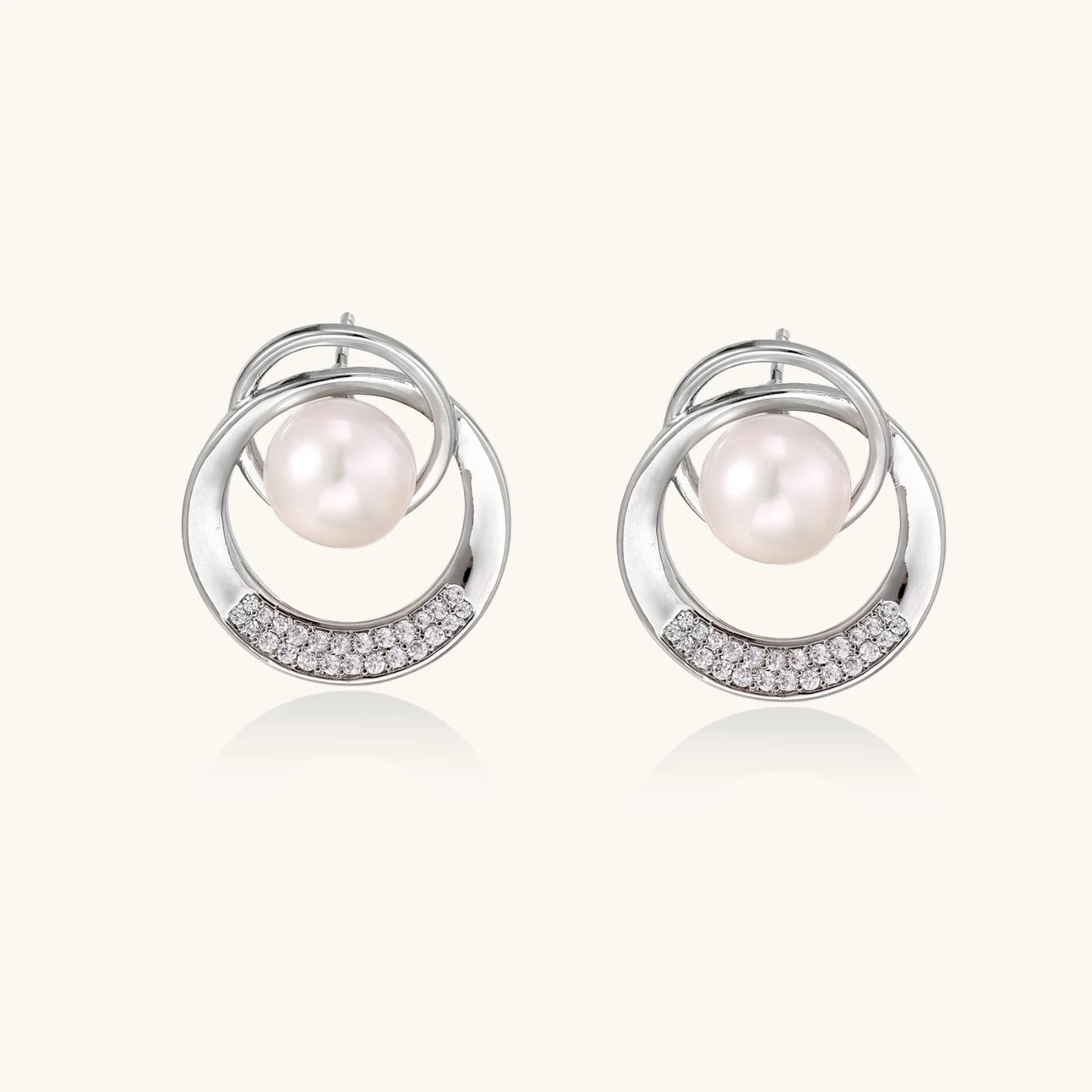White gold-plated brass earrings with circular design, freshwater pearl center, and diamond accents