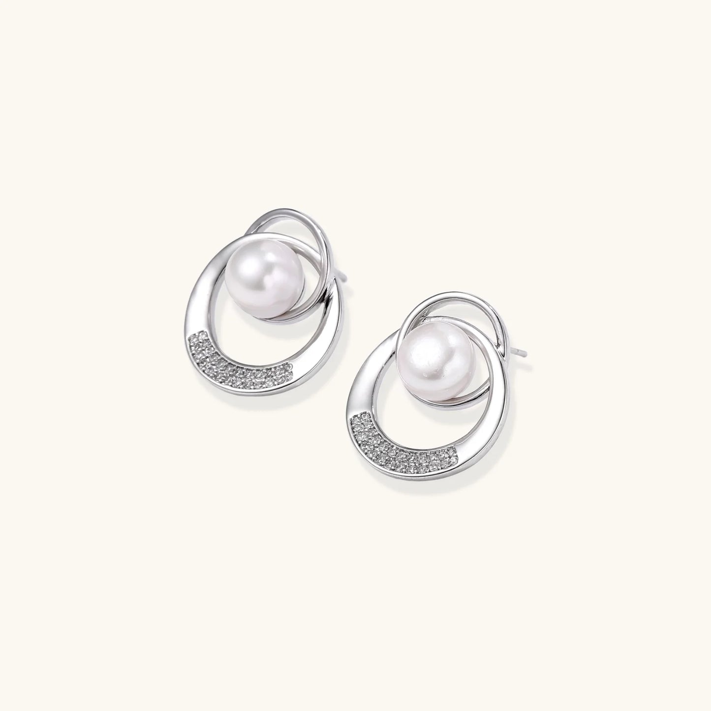 White gold-plated brass earrings with circular design, freshwater pearl center, and diamond accents