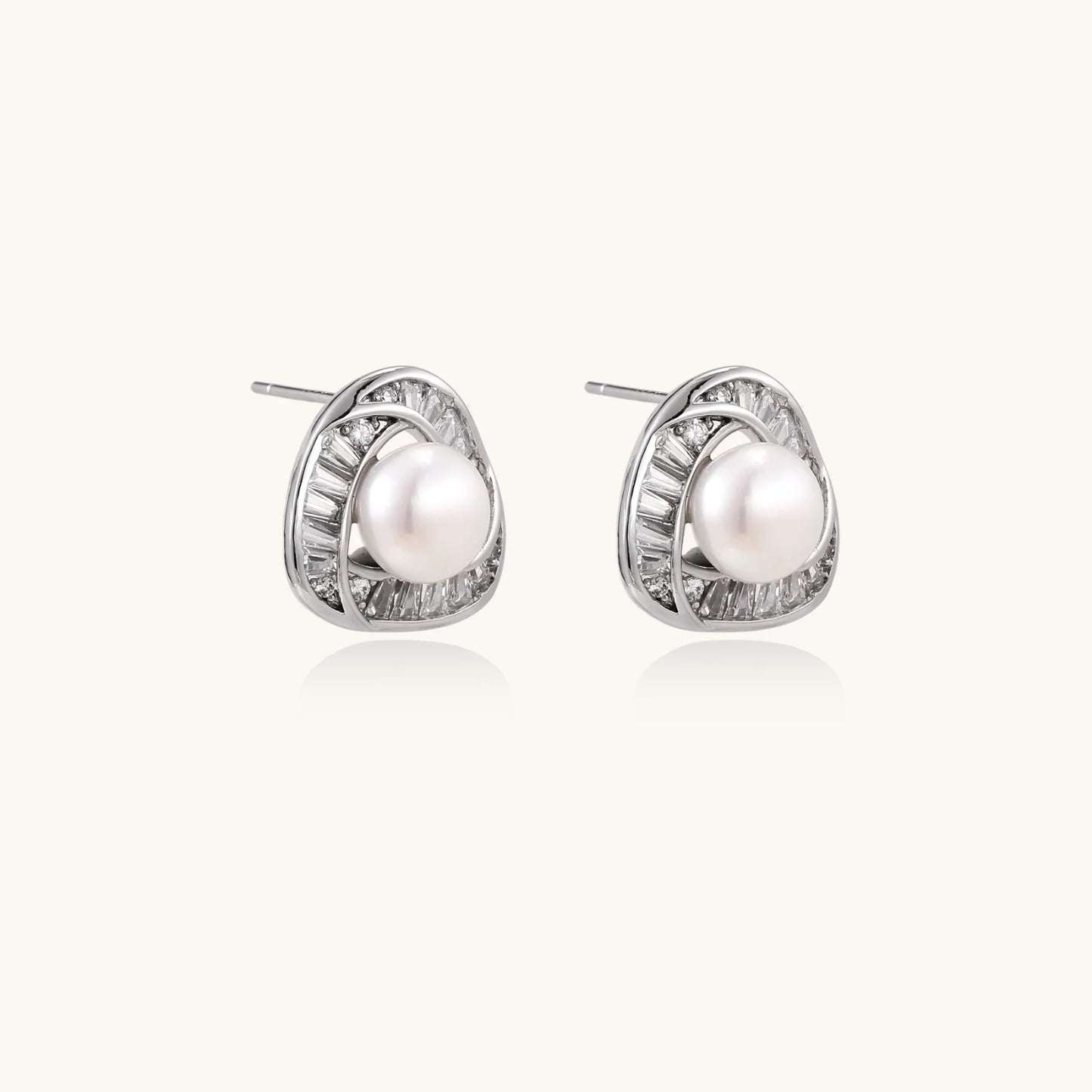 Triangular white gold plated stud earrings with central freshwater pearl and baguette-cut stones on white background