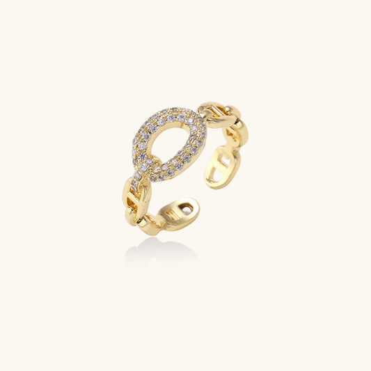 Gold-plated brass chain link ring with one oval CZ-pavé segment on cream background, adjustable cuff style.