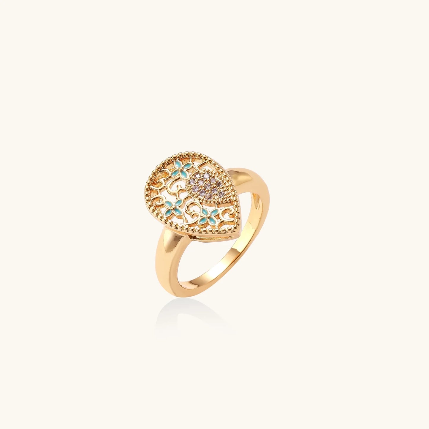 Teardrop-shaped gold-plated ring with turquoise enamel flowers and crystal pavé detail on cream background