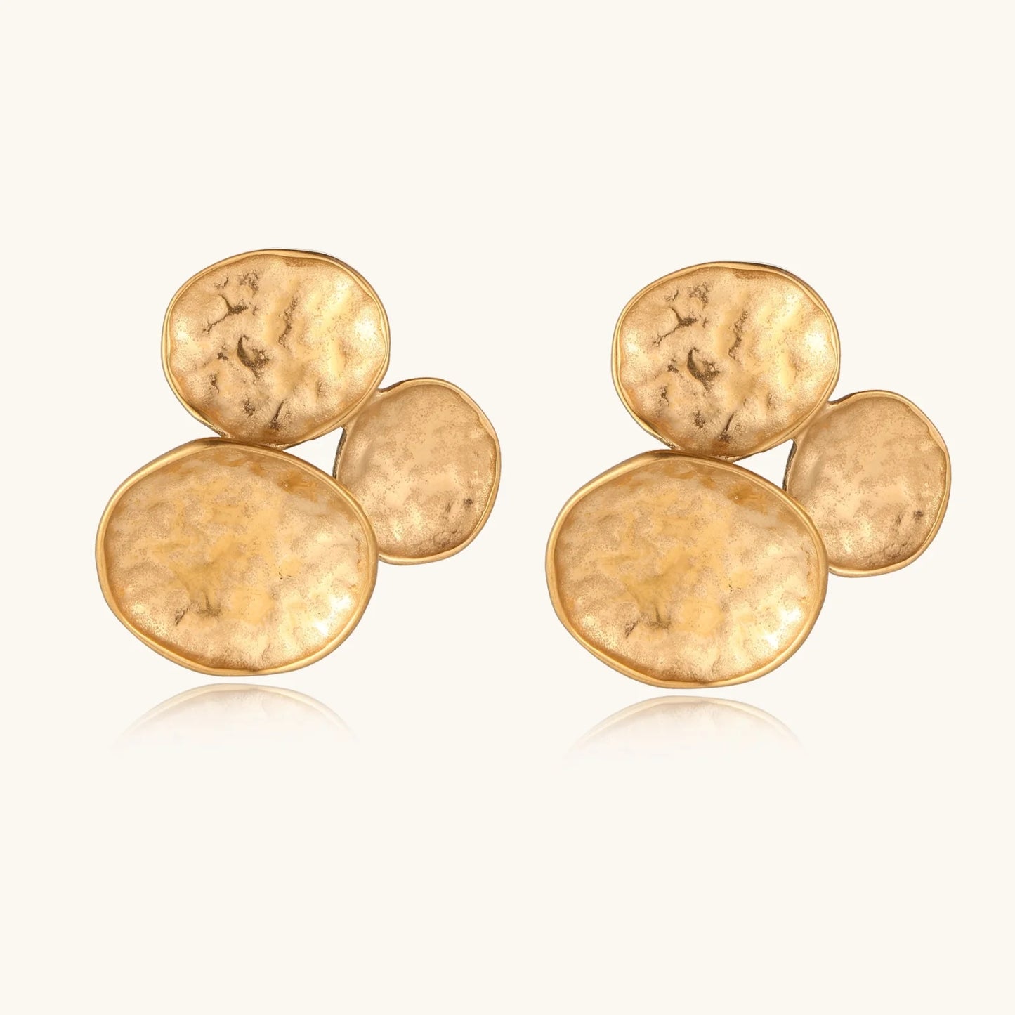 Three hammered gold discs clustered together forming organic statement earrings with textured surfaces