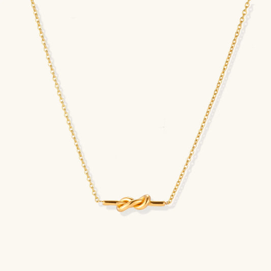 Dainty 18K gold plated necklace with infinity knot pendant on delicate chain against white background
