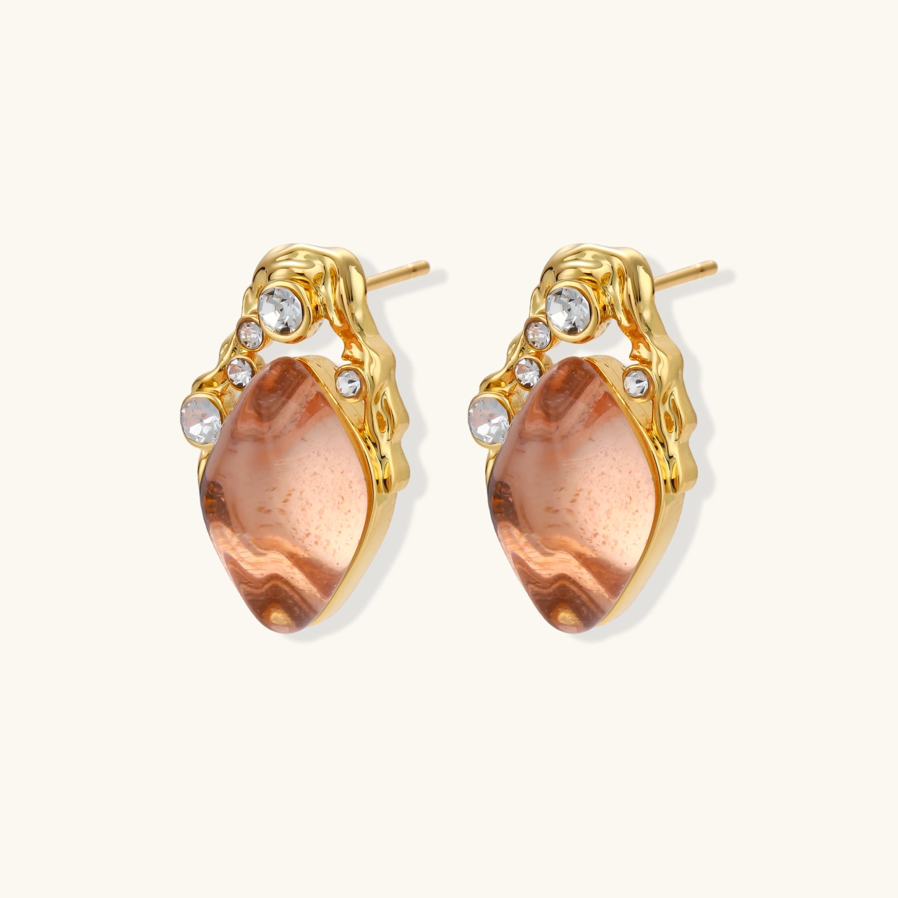 Gold-plated baroque stud earrings with coral-pink liuli stones and cubic zirconia crystals on white background.