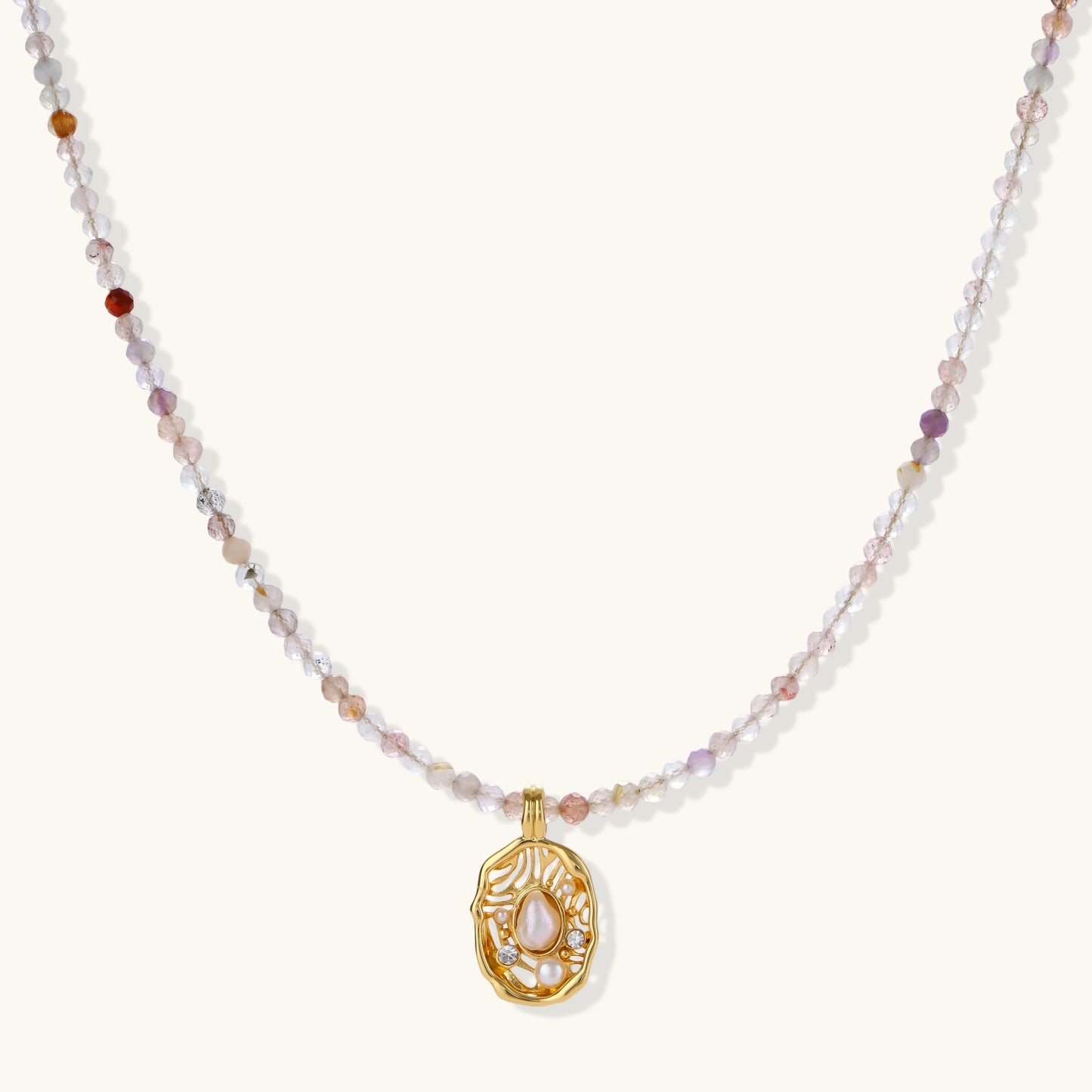 Delicate gold-plated necklace with mixed gemstone beads and ornate oval pendant on white background