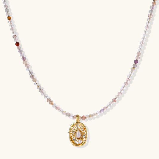 Delicate gold-plated necklace with mixed gemstone beads and ornate oval pendant on white background